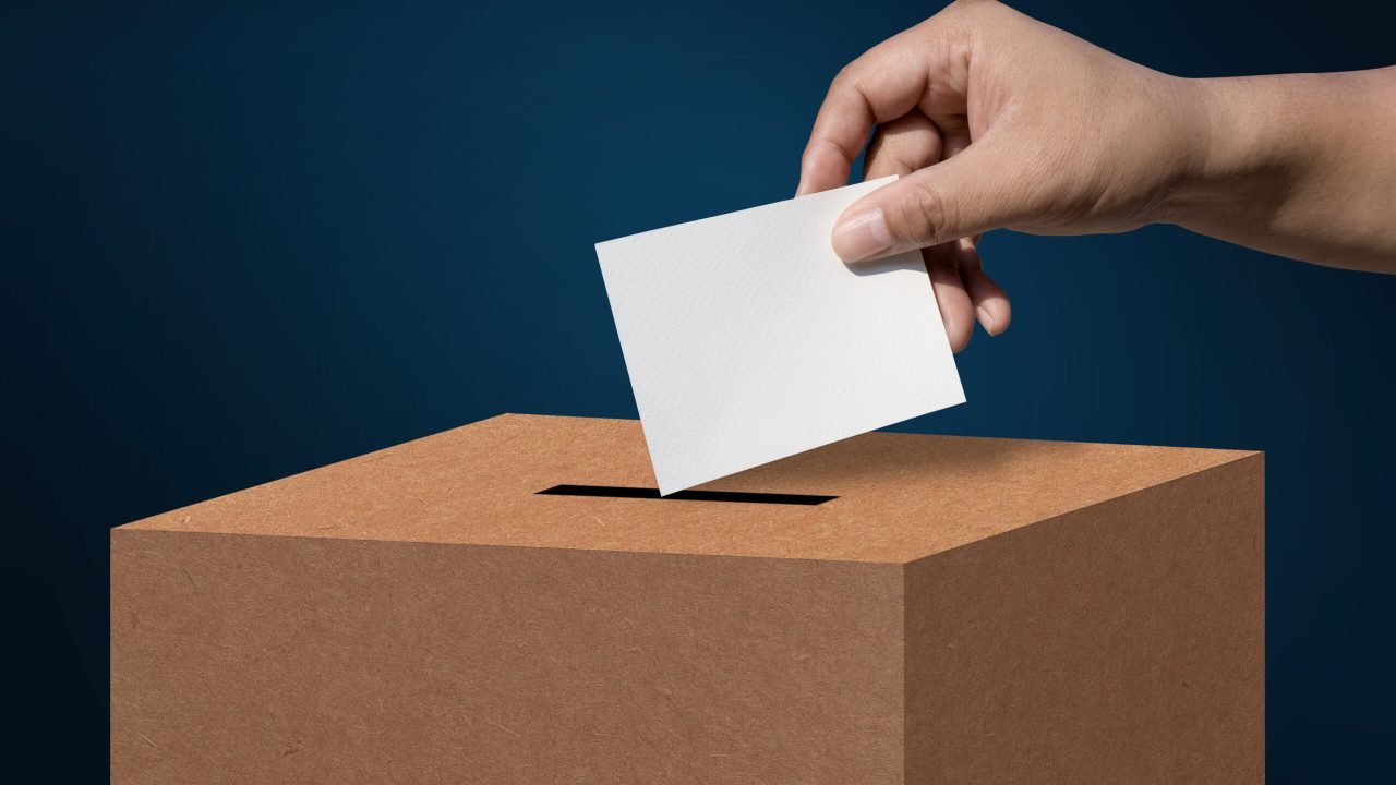 concept vote election Election of members of parliament, president, chief, executive. a ballot paper in hand isolated on background